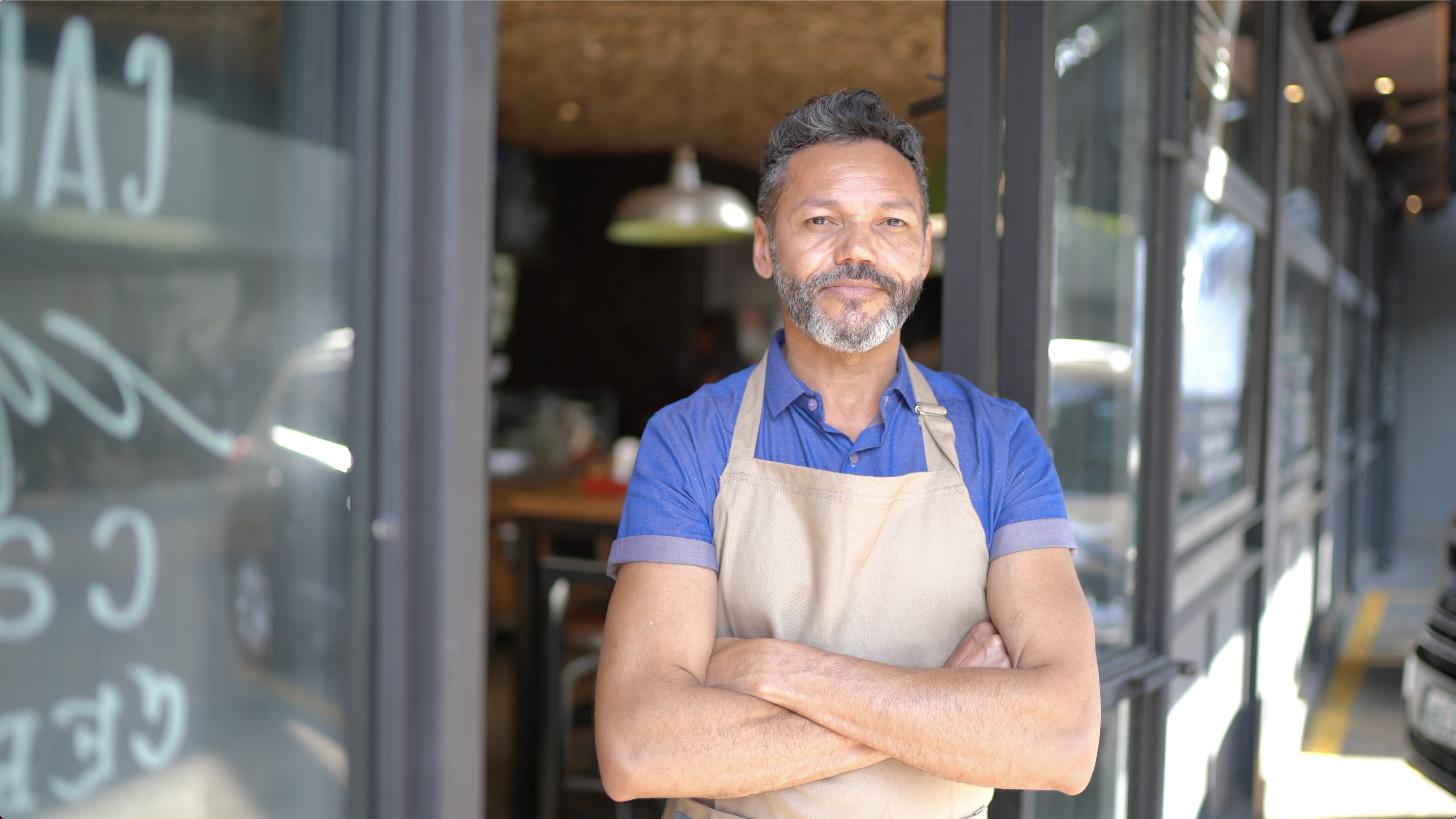 A man wearing an apron stood outside a business