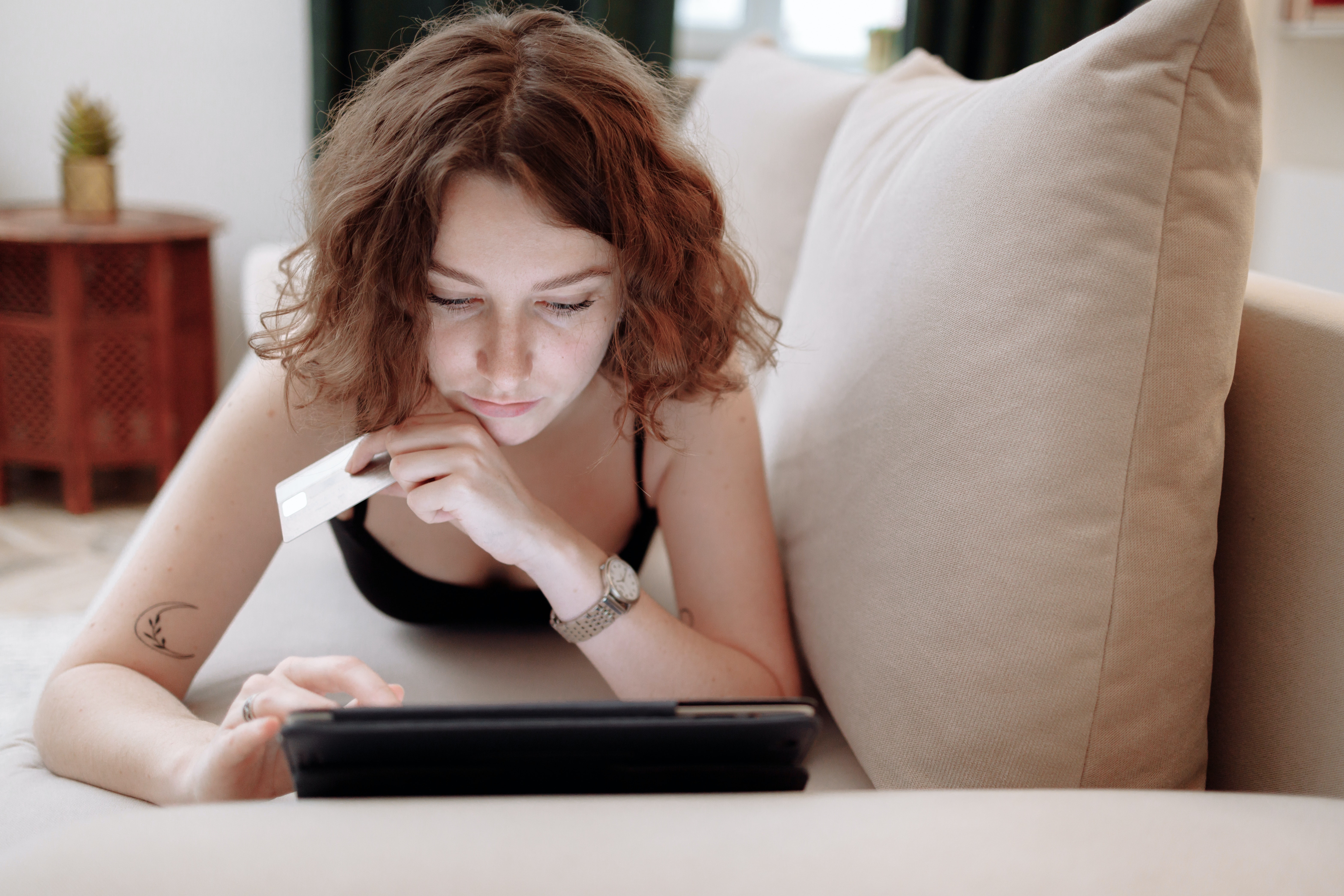 Money saving tips. Woman sat with an ipad holding a bank card.