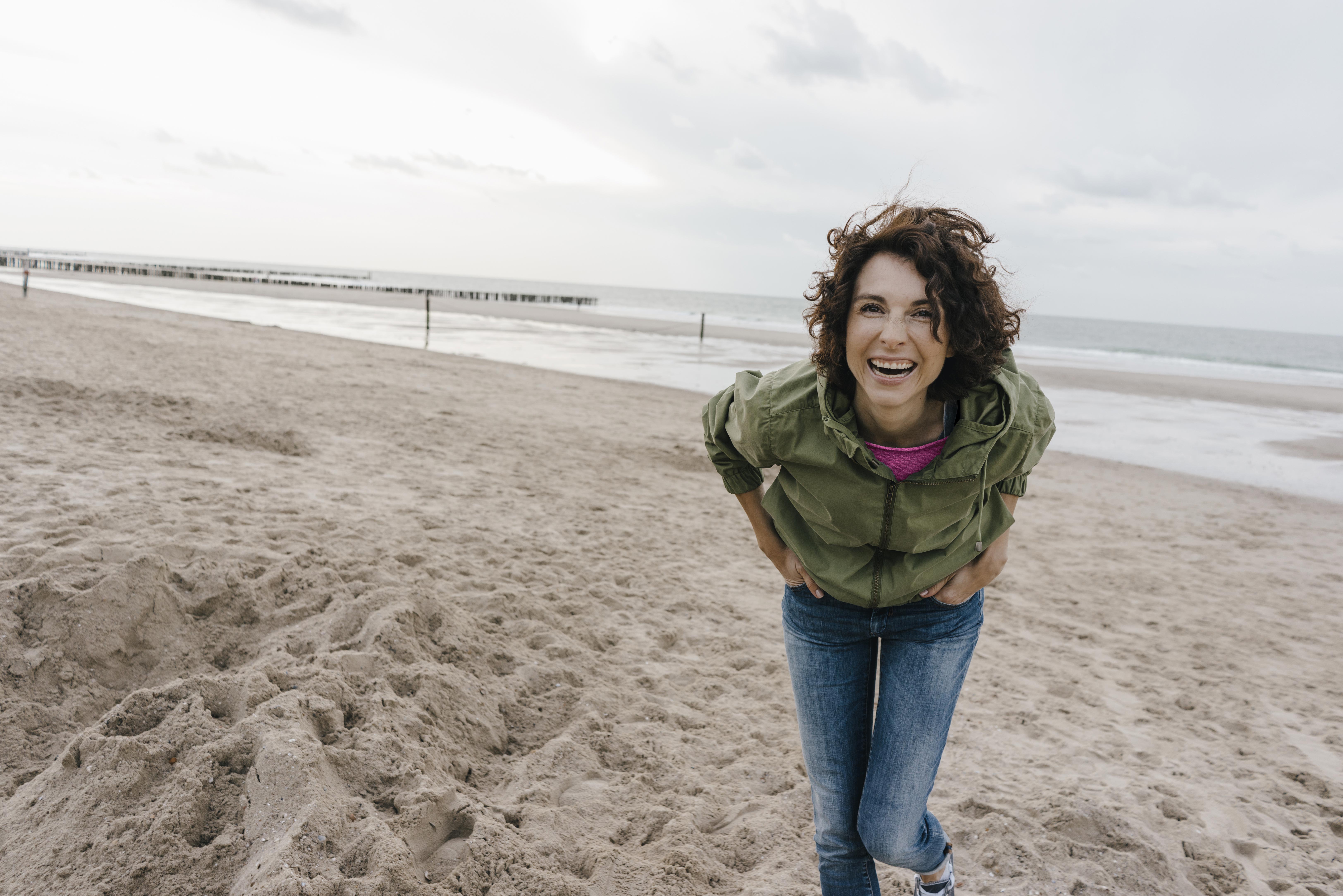 Holiday-let and staycation concept: Woman smiling and laughing on a beach
