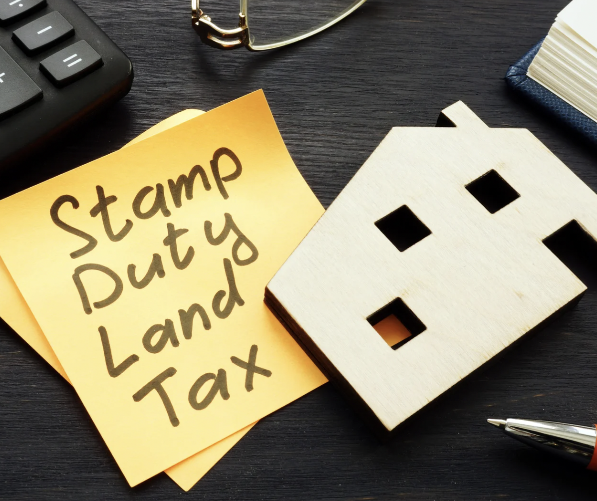 desk with stamp duty post-it and wooden house