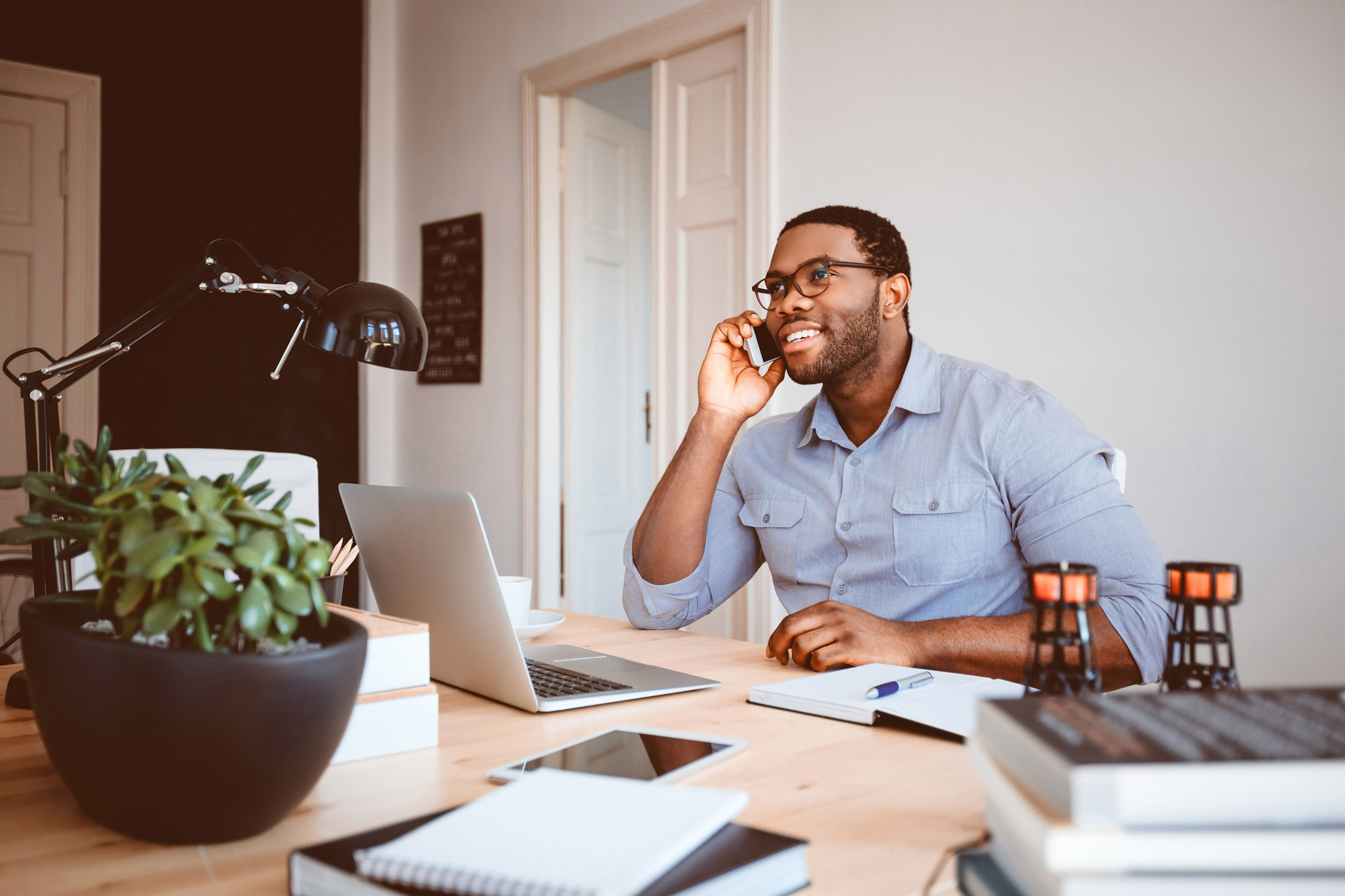 Using a mortgage broker concept: Business man on the phone, sat at table with laptop and paperwork