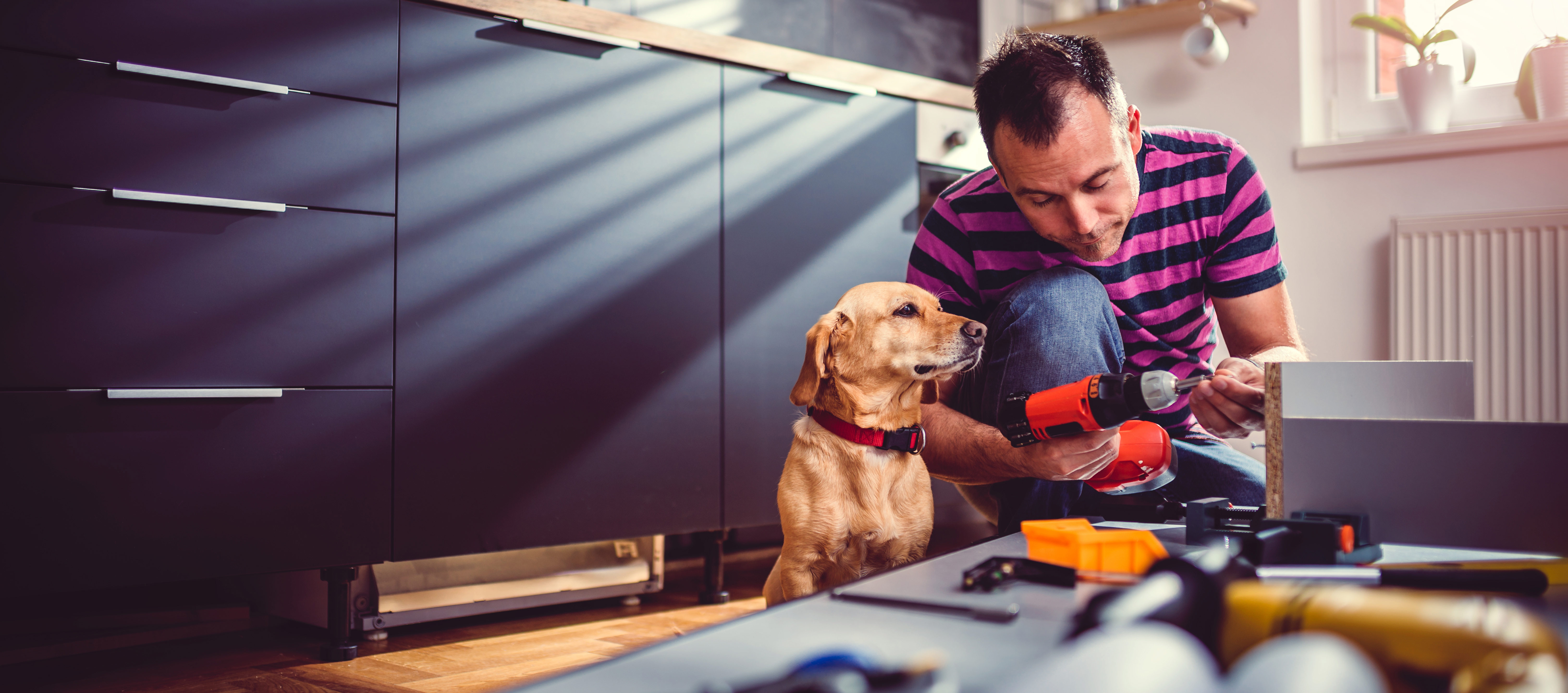 Buy to Let responsibilities concept: Man repairing kitchen cupboards