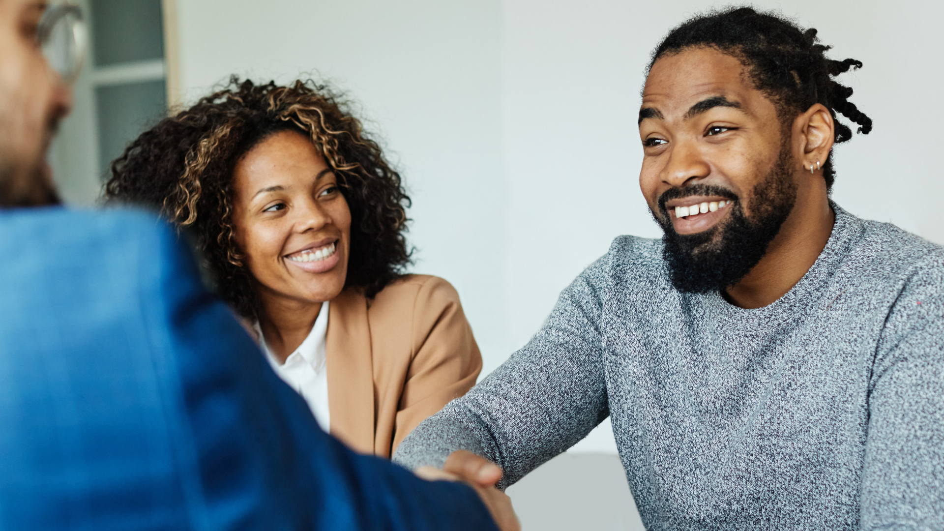 A couple shaking hands with a mortgage advisor.