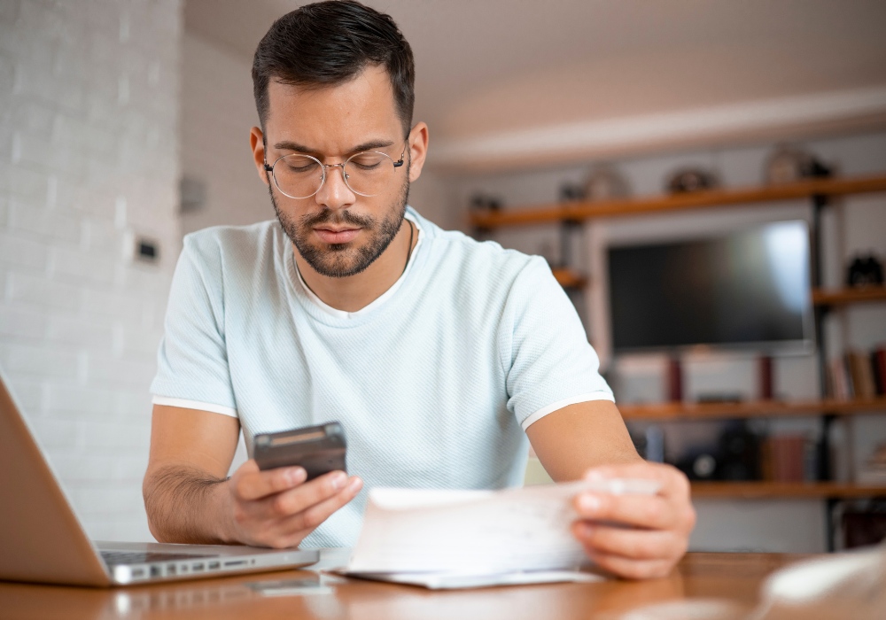 Man sat at a desk with paperwork and a calculator