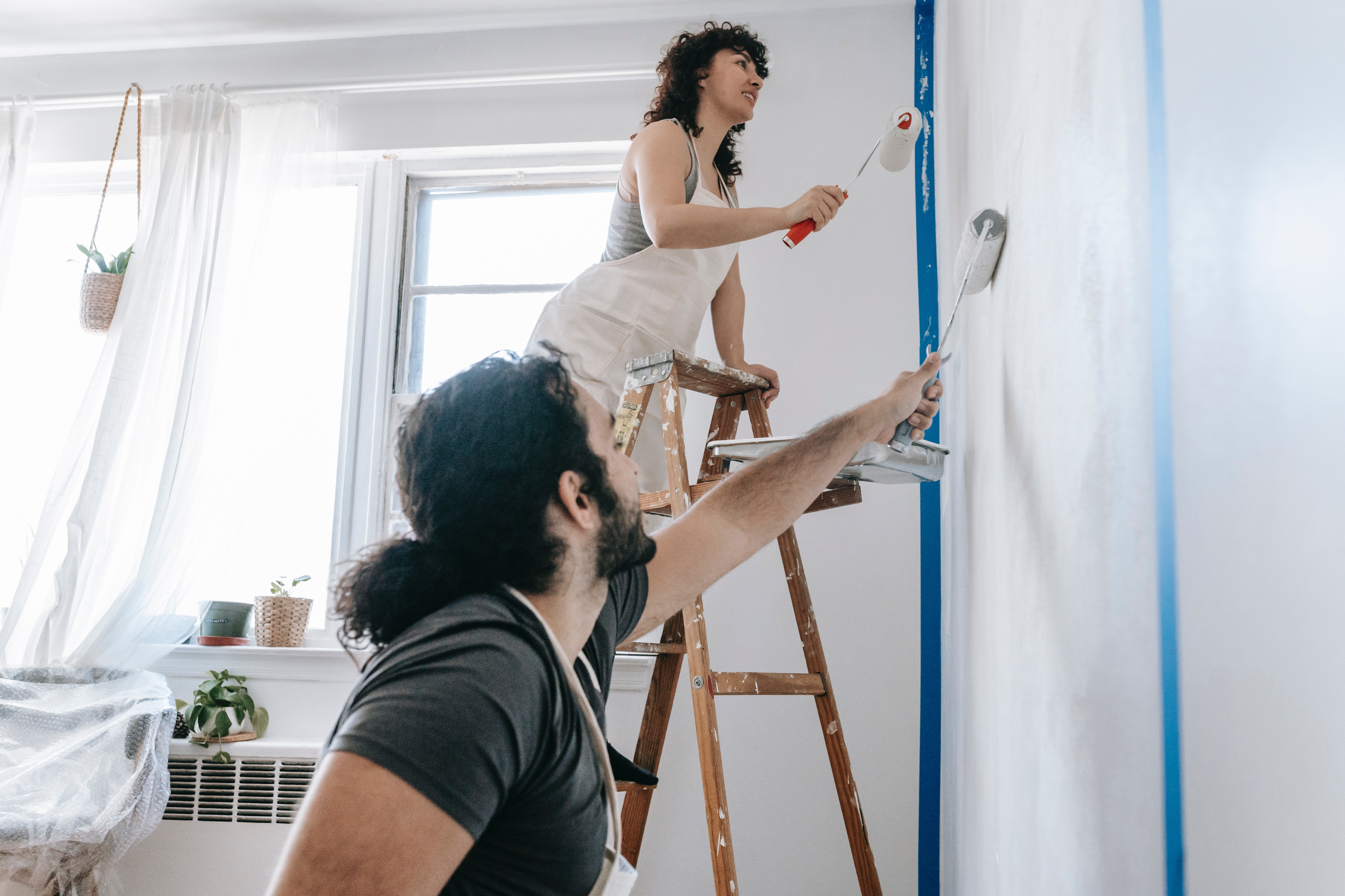 A couple painting a wall in their home.