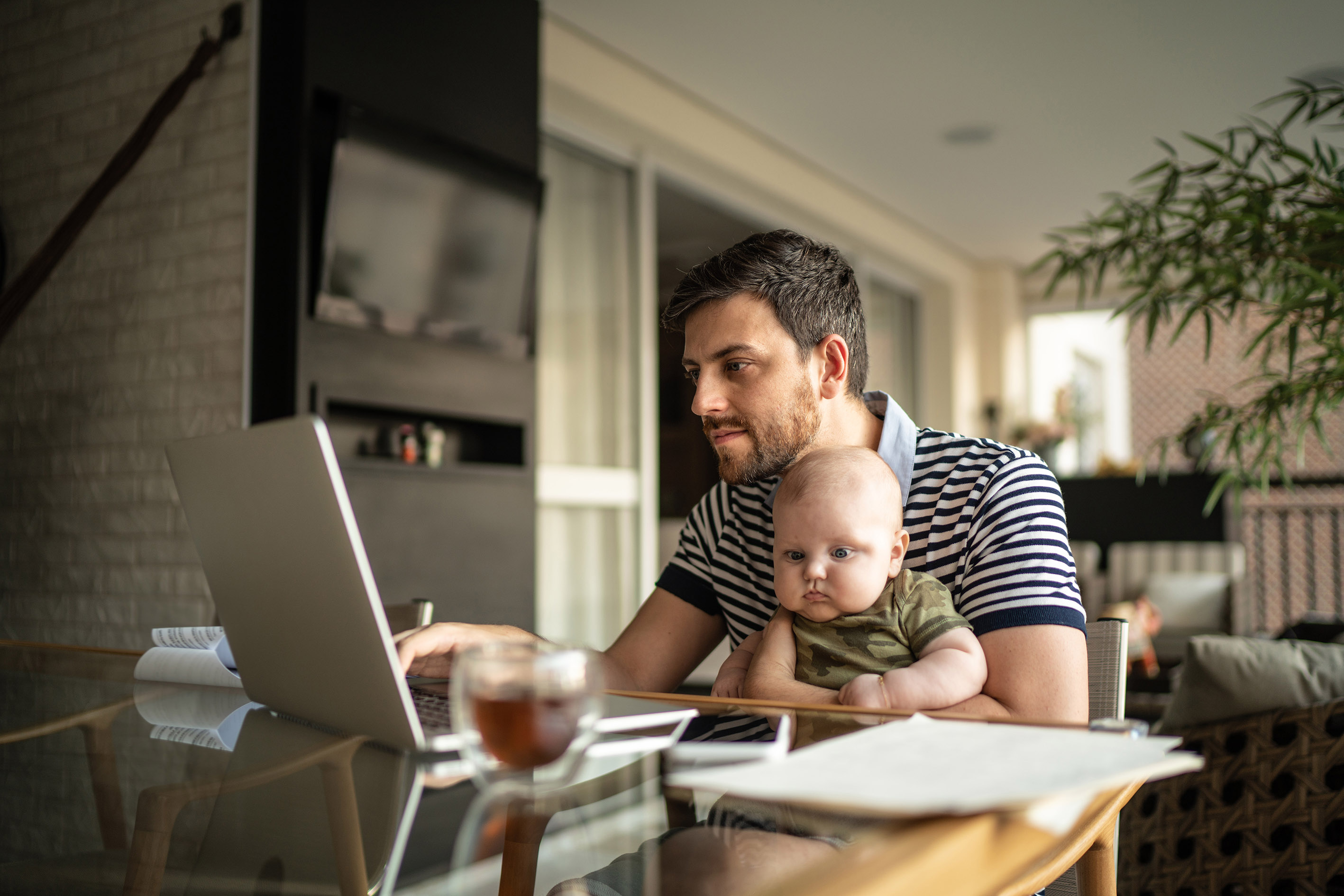 Man sat at table checking laptop to represent checking your credit rating online.