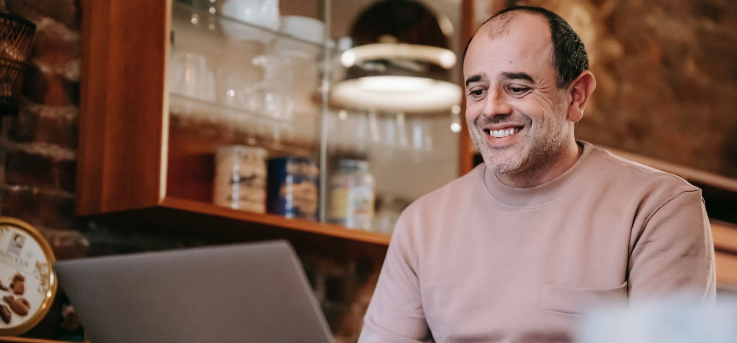 A man smiling at his laptop screen