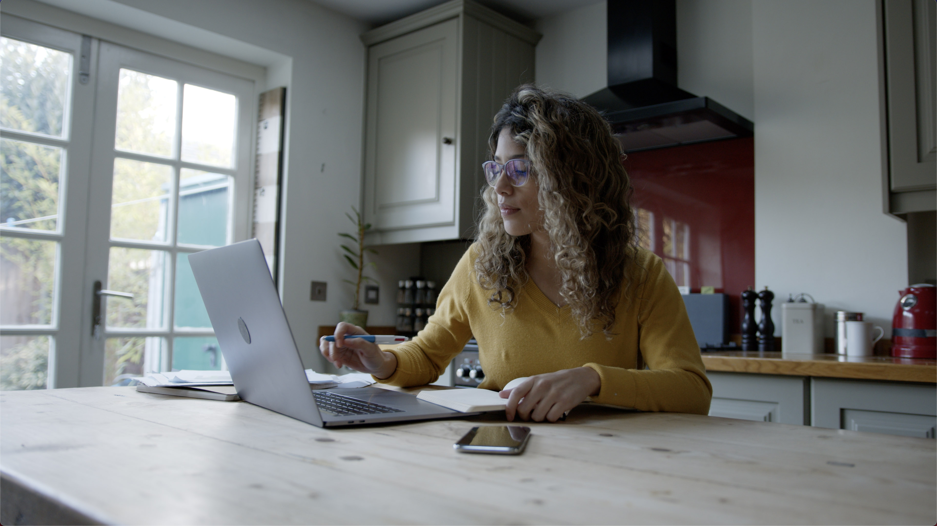 A woman working on a laptop in a kitchen